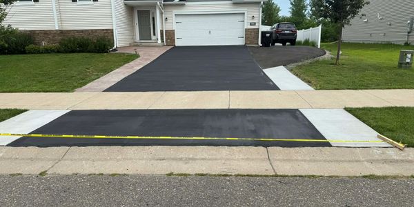 Freshly paved driveway with a measuring tape stretched across the new asphalt.