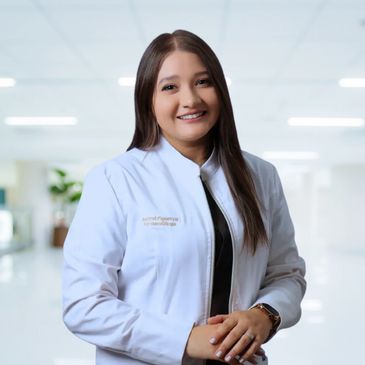 Smiling female doctor in white coat in a bright medical setting.