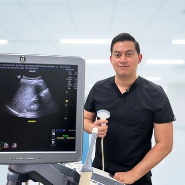 Male medical professional holding ultrasound probe beside ultrasound machine.