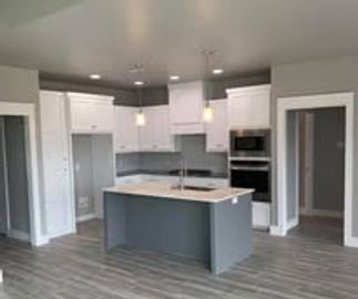 Modern kitchen with gray island and pendant lights.