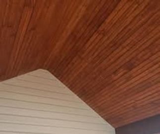 Wooden ceiling with white shiplap wall in a room corner.