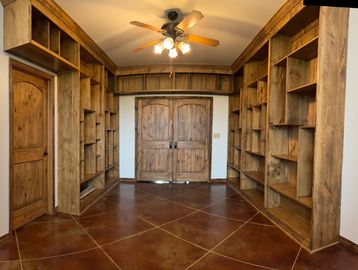 Empty room with wooden shelves, double doors, single door, and ceiling fan.