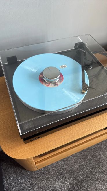 Turntable with a blue vinyl record on a wooden table.