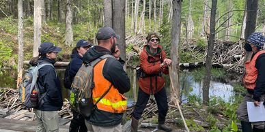Bibi speaking to group at base of beaver dam.