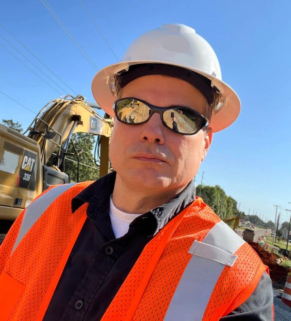Construction worker in safety gear at a worksite.