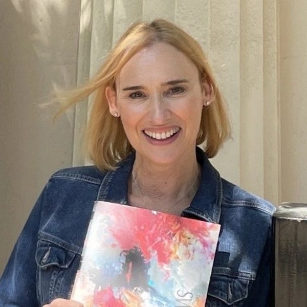 Smiling woman holding colorful artwork.