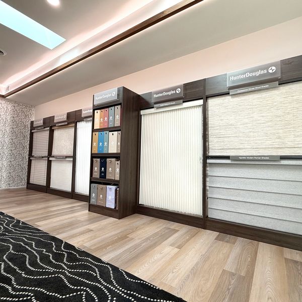 Modern showroom displays various Hunter Douglas window shades and fabric samples.
