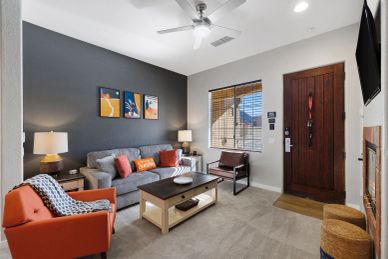 Modern living room with gray and orange accents and wooden furniture.