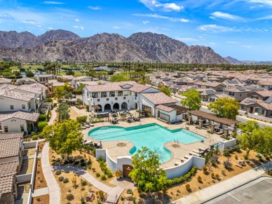 A residential community with a pool and mountain backdrop under a clear sky.