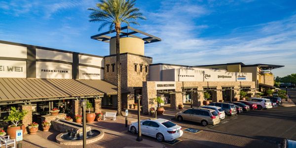 Shopping plaza with various stores and parked cars.