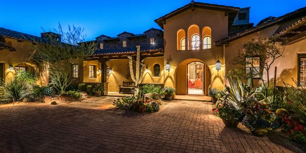 Warmly lit courtyard of a Mediterranean-style home at dusk.