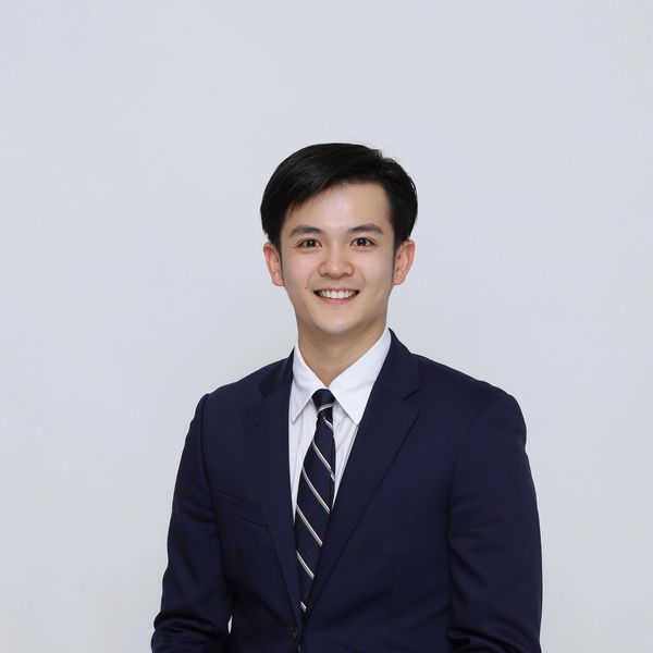 Young man in a navy suit smiling.