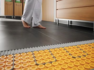 Person standing barefoot on a heated floor tile system in a room.