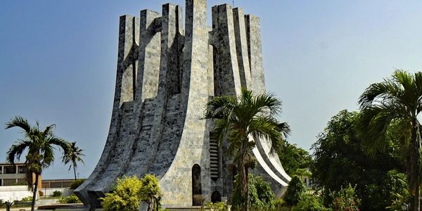 Unique modern stone monument with curved design and palm trees.