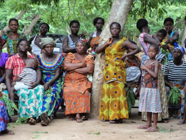 Group of women and children in colorful traditional clothing outdoors.