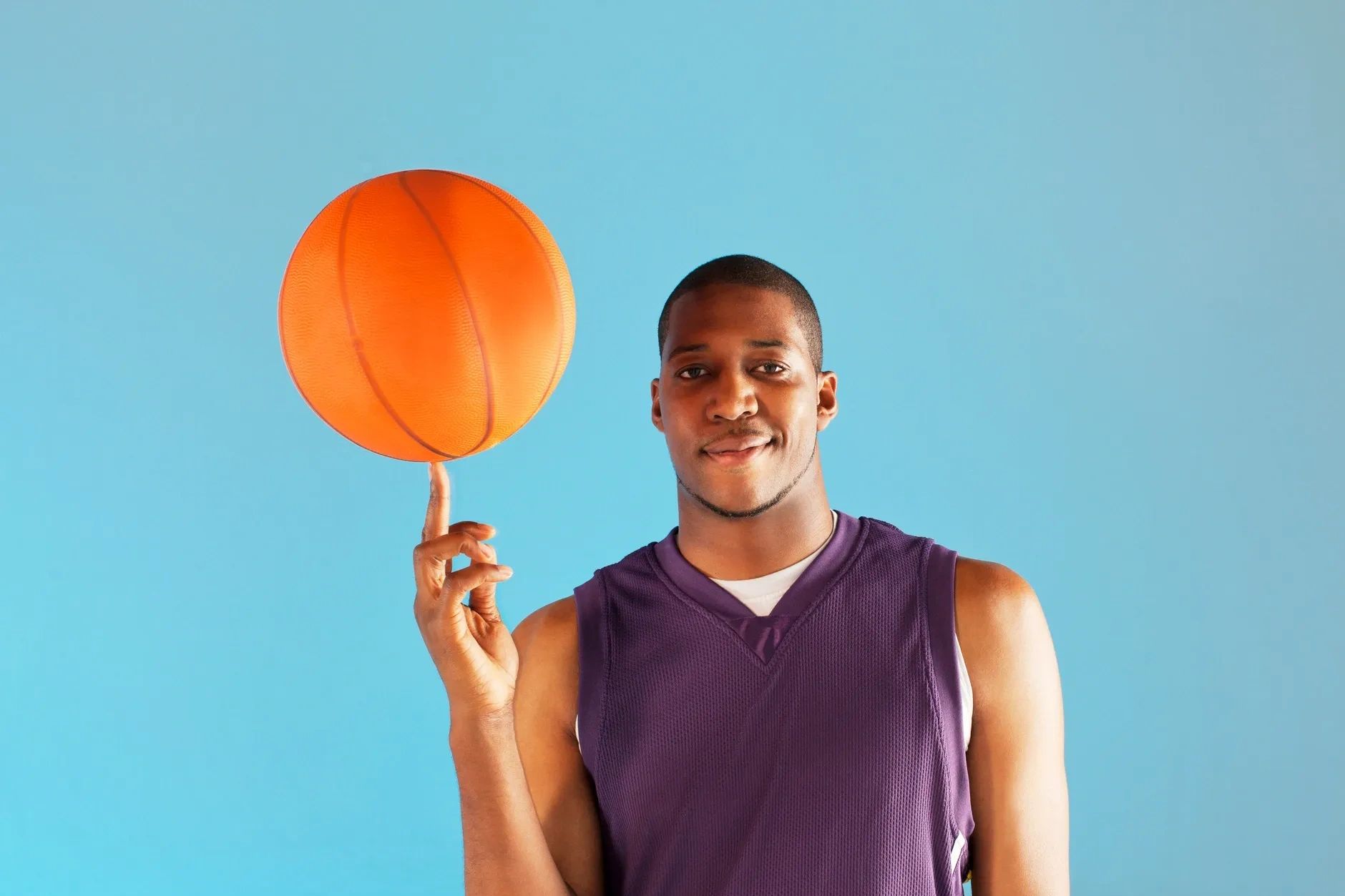 A man spinning a basketball on his finger, illustrating happiness is choices we make daily.