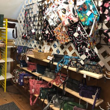 Store display of colorful handbags on shelves and wall hooks.