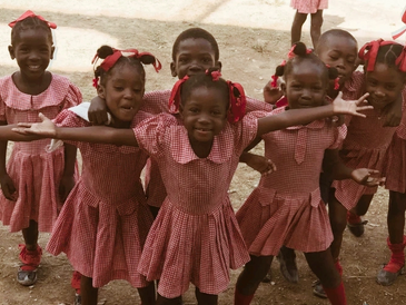 Happy children in matching red checkered school uniforms posing outdoors.