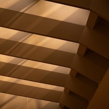 Sunlight casting shadows on a modern architectural ceiling with beams.