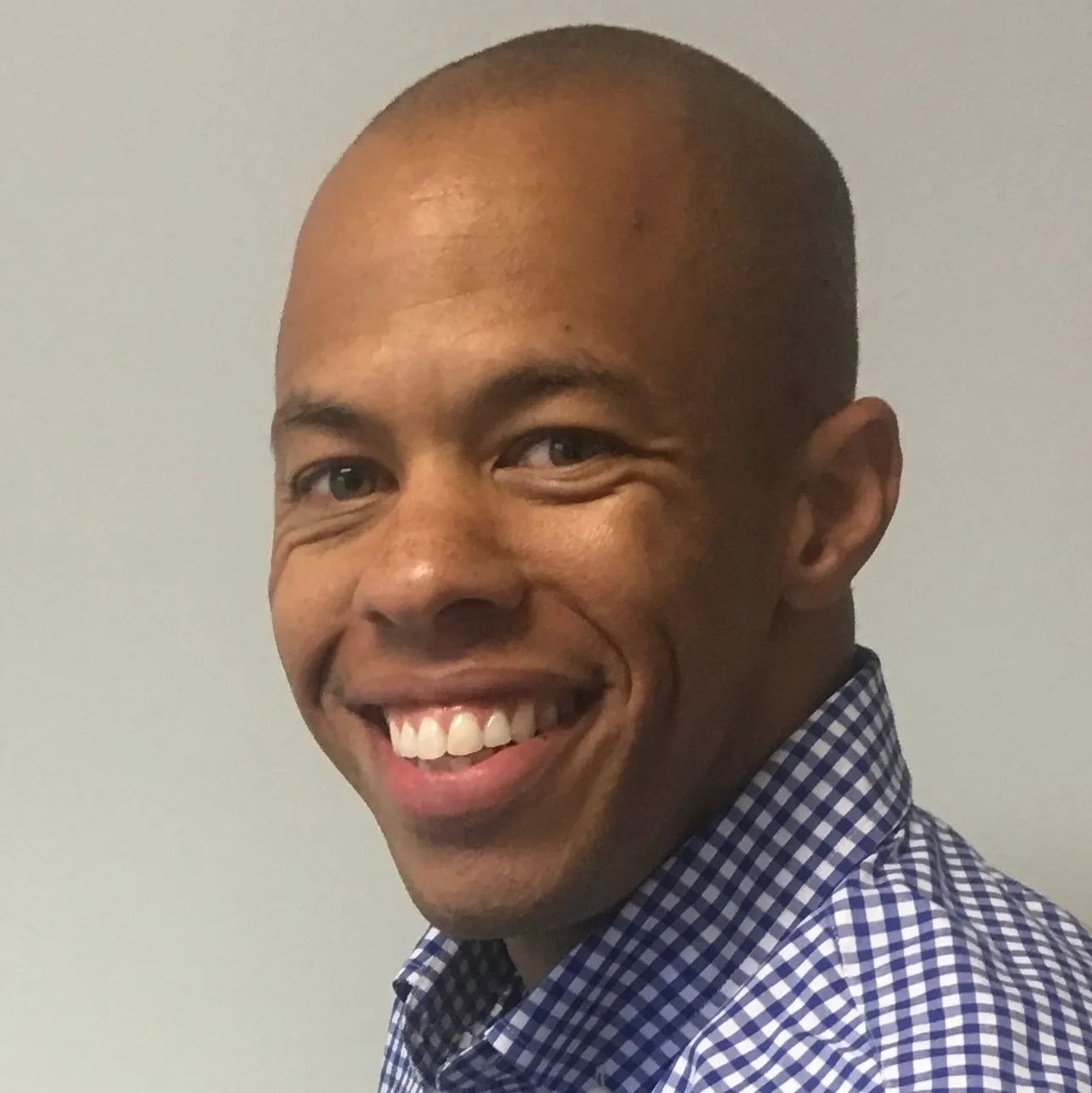 Smiling man in a checkered shirt looking at the camera.