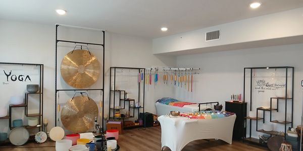 A serene yoga and sound therapy room with gongs and colorful instruments.