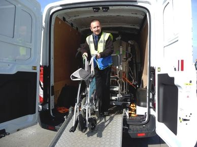 Man unloading a wheelchair from a van