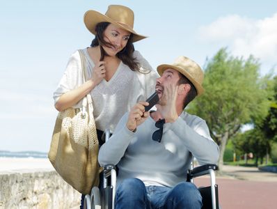 a happy couple with man in a wheelchair on holiday.