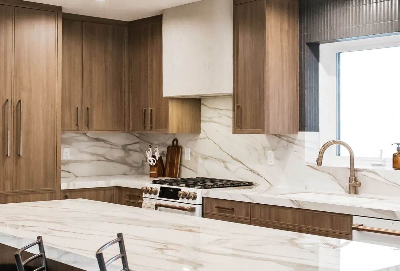 Modern kitchen with marble countertops and wooden cabinets.