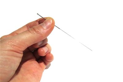hand holding tiny acupuncture needle