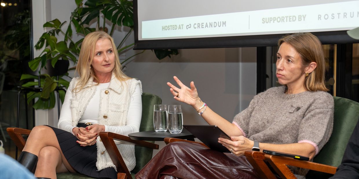 Two women engaged in a serious discussion during a panel event.