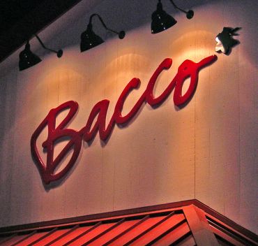 Illuminated sign reading 'Bacco' on a building.