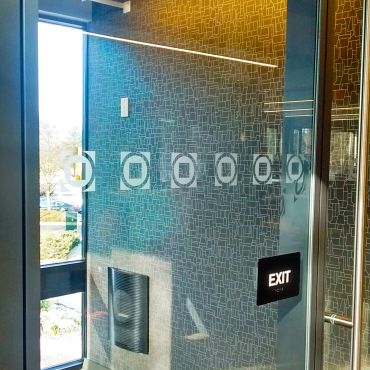 Glass door with exit sign and patterned wall inside a building.