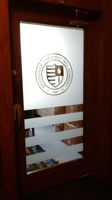 Wooden door with Springside Chestnut Hill Academy logo and frosted glass panels.