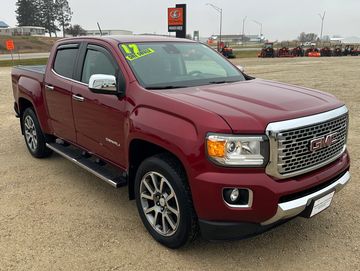 Red 2017 GMC pickup truck parked outdoors on gravel.
