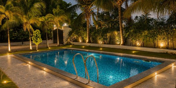 A beautifully lit swimming pool surrounded by palm trees at night.