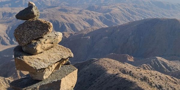 a photo of rocks balancing on one another with mountains in the back