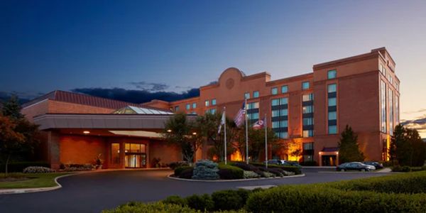 A large brick hotel building at dusk with flags and well-lit entrance.