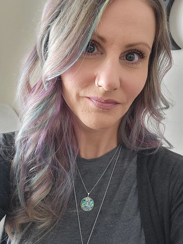 Woman with multi-colored hair and a pendant necklace.