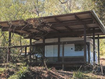 A rustic shelter housing a camper in a wooded area.