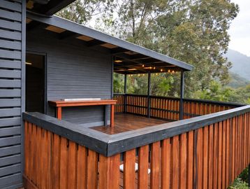 Wooden outdoor deck with railing and string lights overlooking lush greenery.