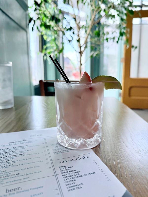 pink, creamy mocktail with fresh sliced strawberry and lime wedge garnish