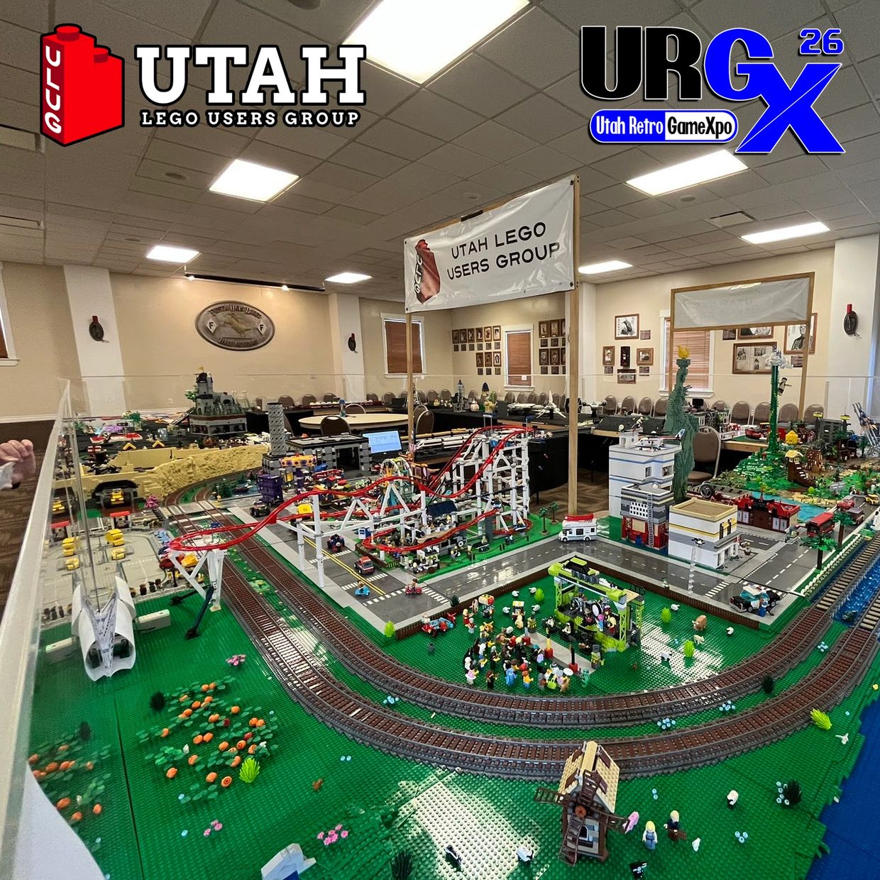 Detailed LEGO city display with roller coaster and train tracks at Utah LEGO Users Group event.