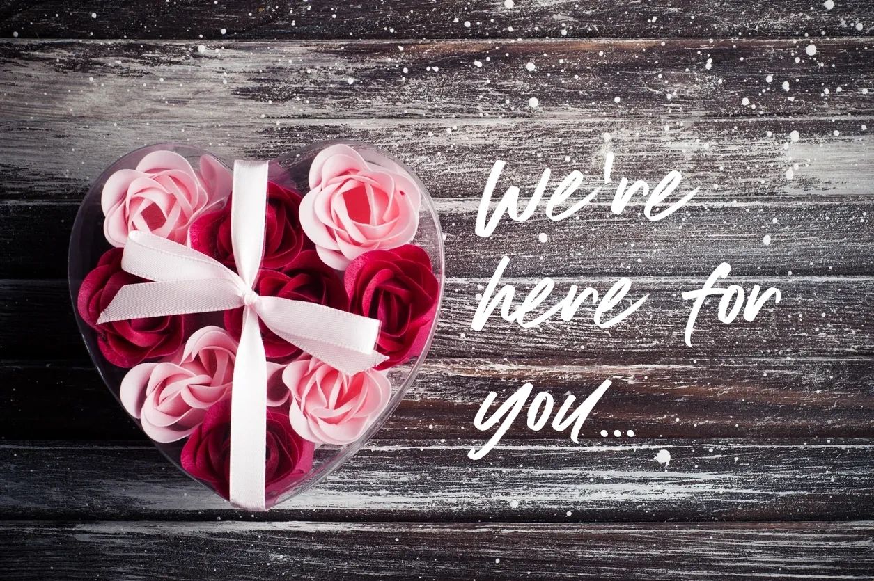 Heart-shaped box with roses and supportive message on wooden background.