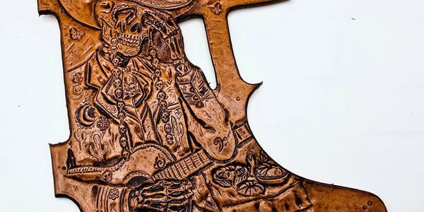 Intricately carved leather artwork depicting a skeletal figure playing guitar.