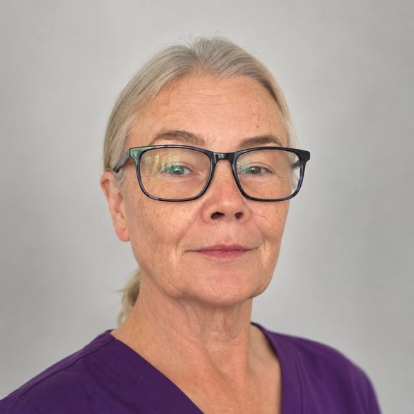 Portrait of an older woman wearing glasses and a purple top.