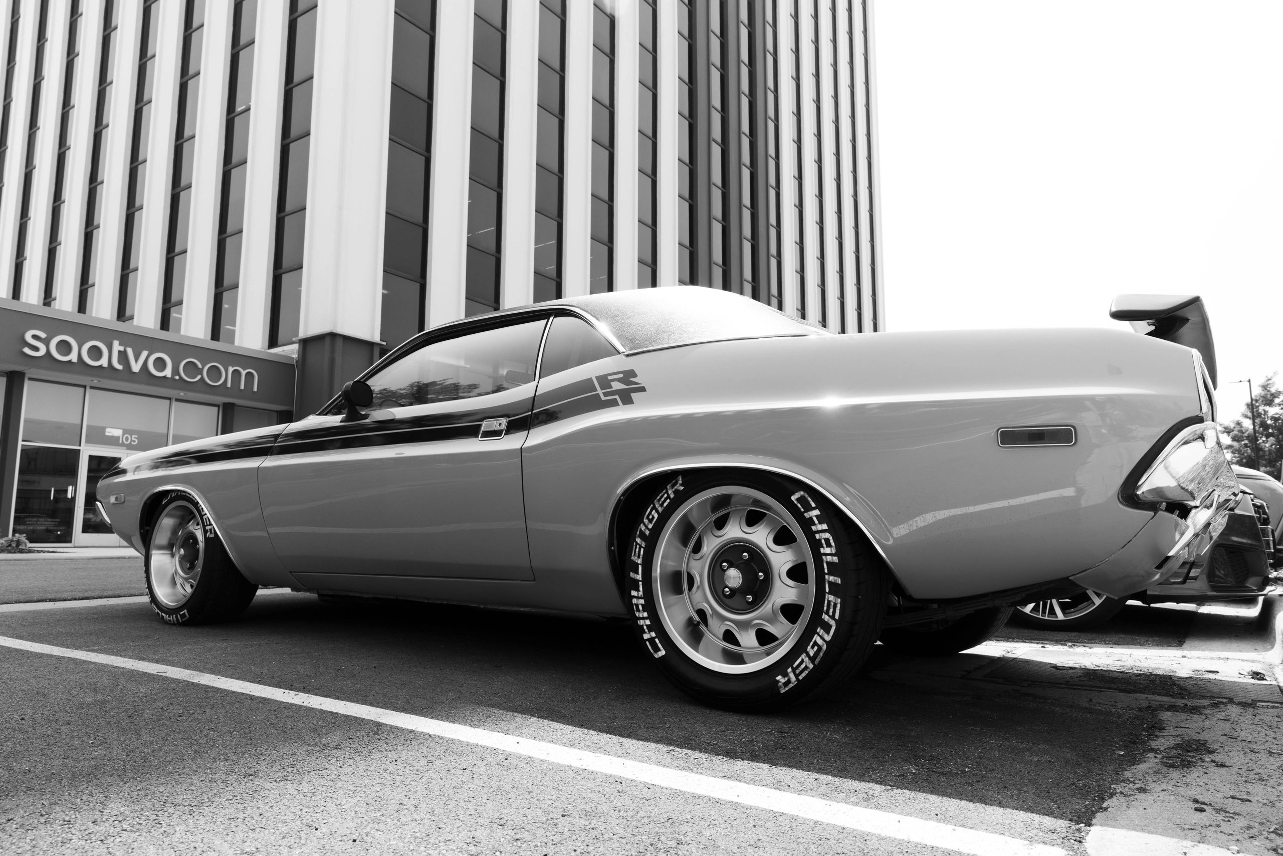 Classic muscle car parked outside a modern building.