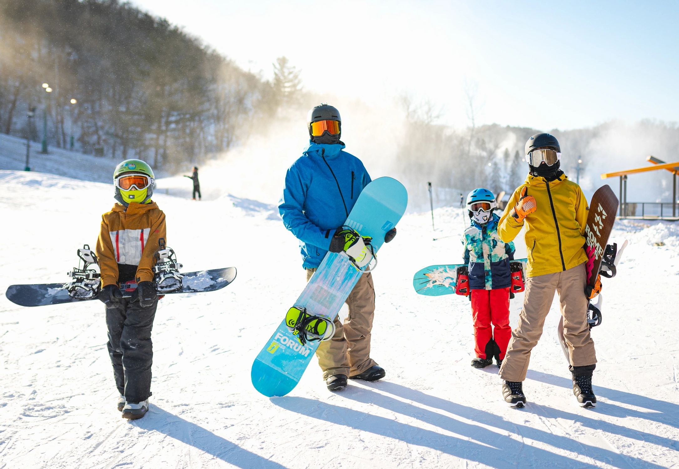 Four snowboarders posing on a sunny snowy mountain.