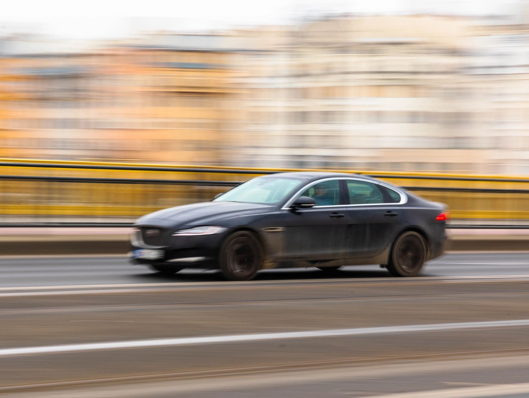 Black luxury car speeding on city road.