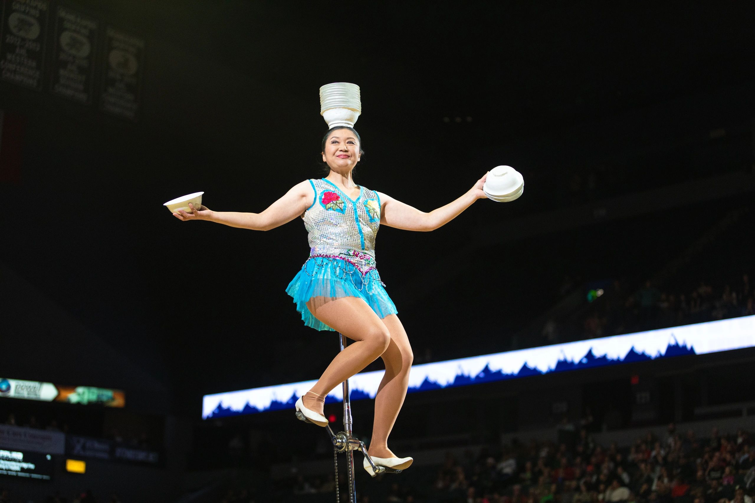 A performer balancing bowls while riding a unicycle.