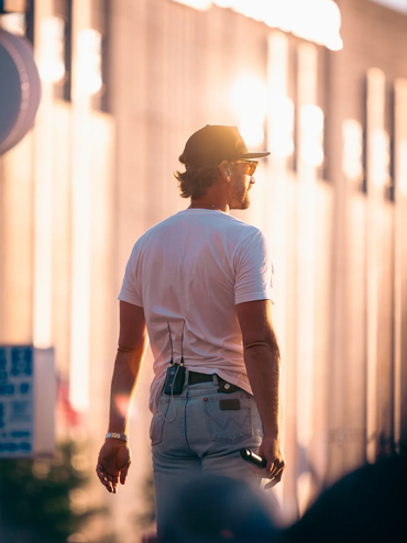 Man in white shirt standing with tech devices attached.